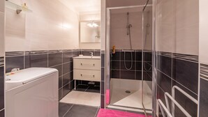 A modern bathroom with a glass-enclosed shower, a white sink, and a vanity with drawers. - Coeur d'Azur - apt climatisé - 1km plage (Saint Raphael)