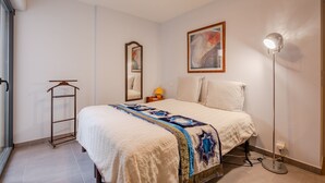 A bedroom with a bed, a bedside table, a lamp, a wardrobe, and a painting on the wall. - Coeur d'Azur - apt climatisé - 1km plage (Saint Raphael)