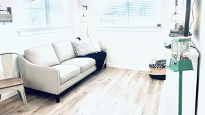 Una sala de estar moderna con un sofá blanco, piso de madera y una máquina expendedora verde de bolitas de goma.