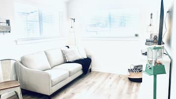 Un salon moderne avec un canapé blanc, un plancher en bois et une machine à bonbons verte.