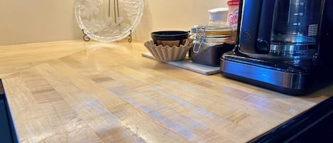 Een aanrecht met een koffiezetapparaat, een glazen pot en een koffiebus.