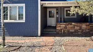 A two-story house with a stone foundation, a front porch, and a covered entryway.