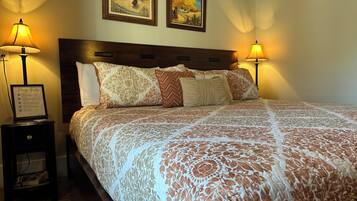 A neatly made bed with a patterned bedspread, two framed pictures on the wall, and two bedside lamps.