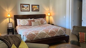 A bedroom with a bed, two bedside lamps, a ceiling fan, and two framed pictures on the wall. - King Mountain Suite (Westcliffe)