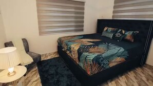 A bedroom with a bed, a nightstand, a lamp, and a window with blinds.