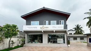 A two-story building with a sign for 'MAQUEN Royal Imports' offering kitchen, bed, bath, and more.