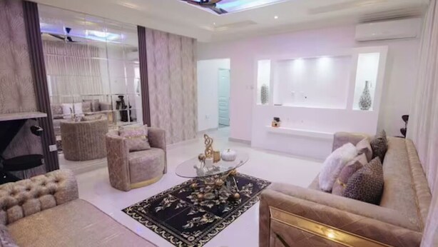 A modern living room with a sofa, armchairs, a coffee table, and a fireplace.