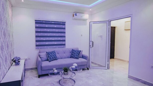 A modern living room with a grey sofa, patterned cushions, a glass coffee table, and a decorative vase. - B&B Charming bed & breakfast in gorgeous Accra with WiFi, AC (Accra)