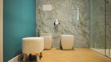 Un baño moderno con pared de mármol, cabina de ducha de vidrio y un inodoro blanco.