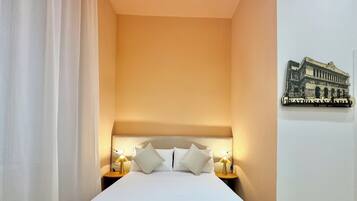 Ein Hotelzimmer mit einem Bett, zwei Nachttischen mit Lampen, einem weißen Vorhang und einer Wanddekoration.
