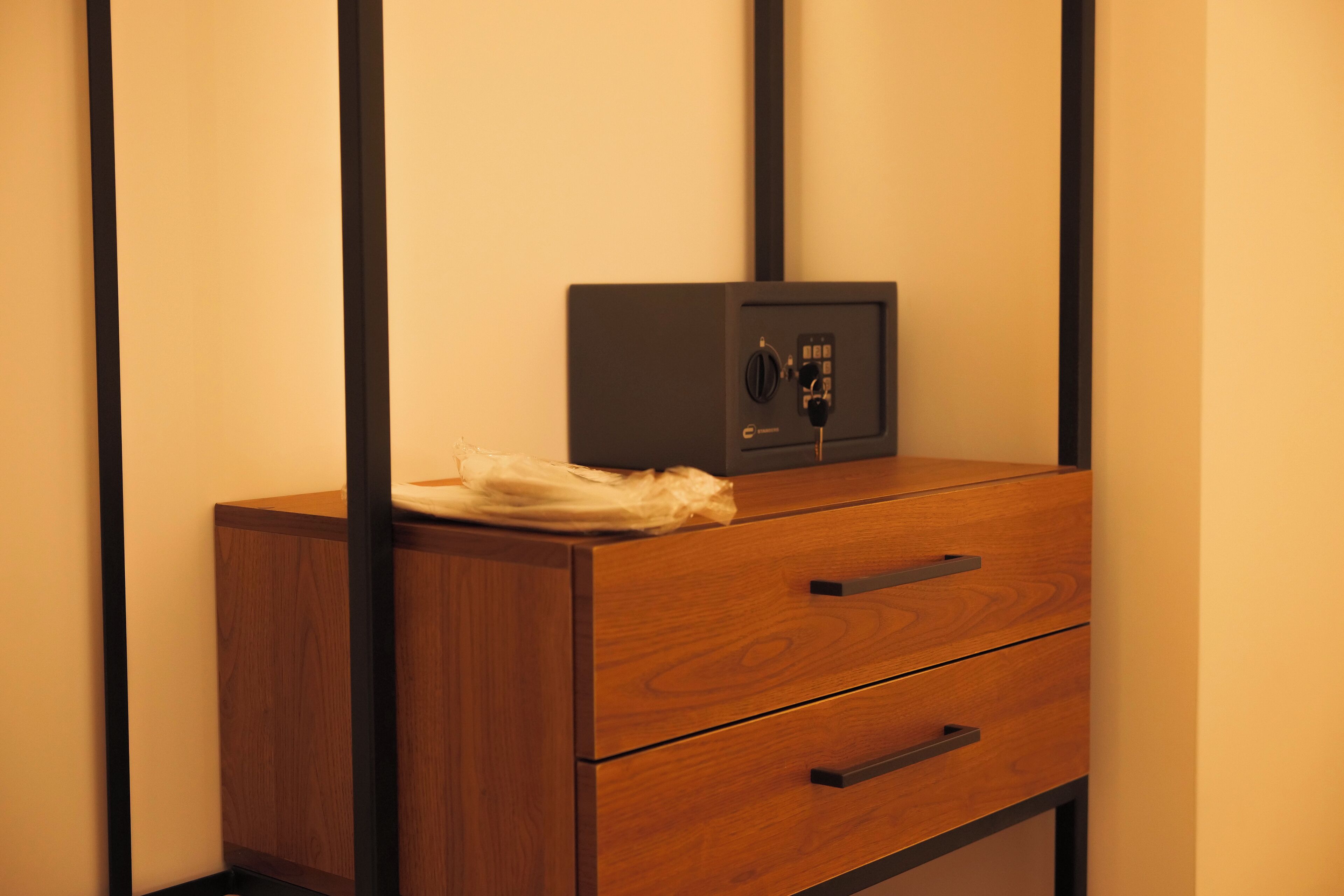 A wooden cabinet with a black safe on top and two drawers.