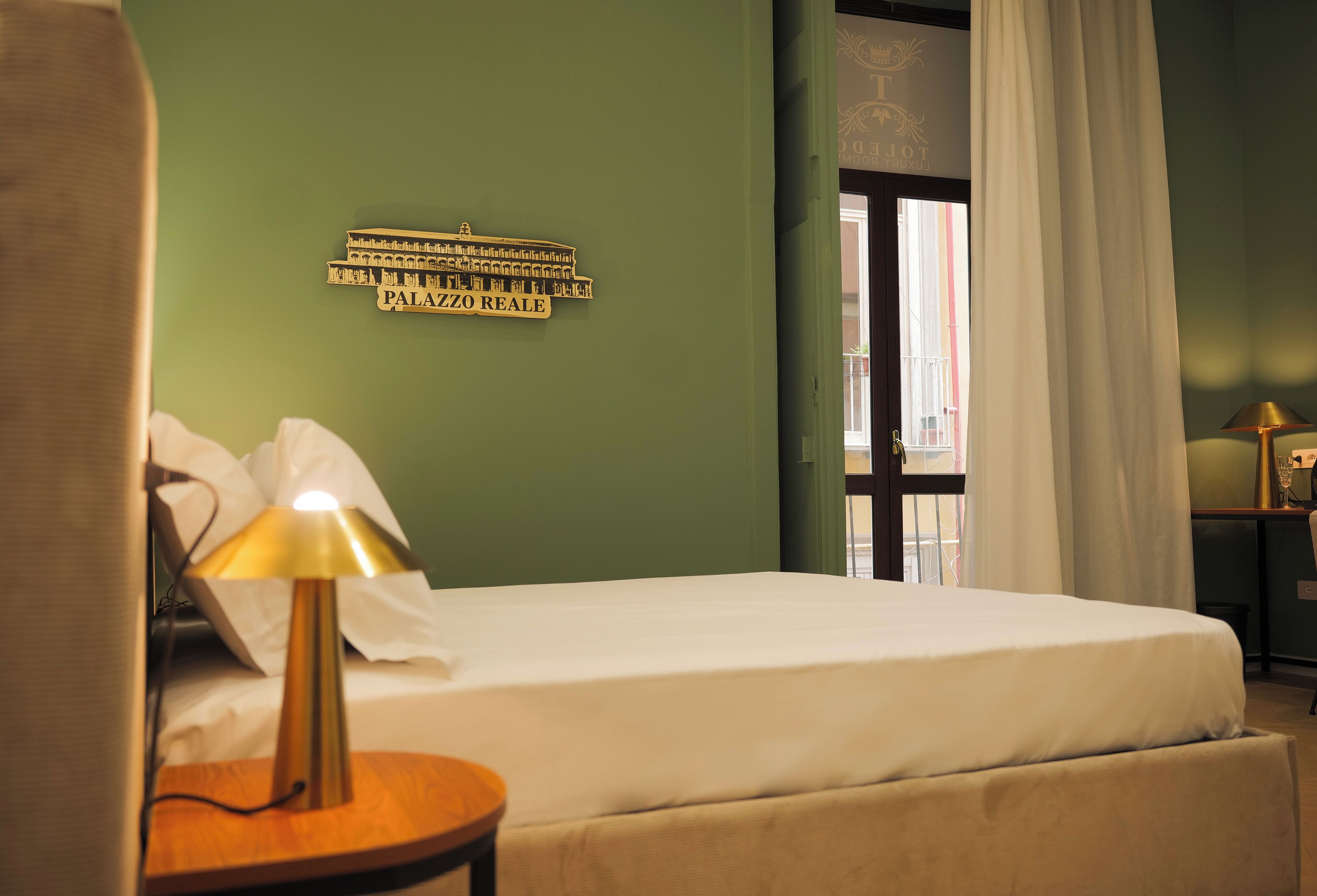 A hotel room with a bed, a lamp, a sign on the wall, and a window with curtains.