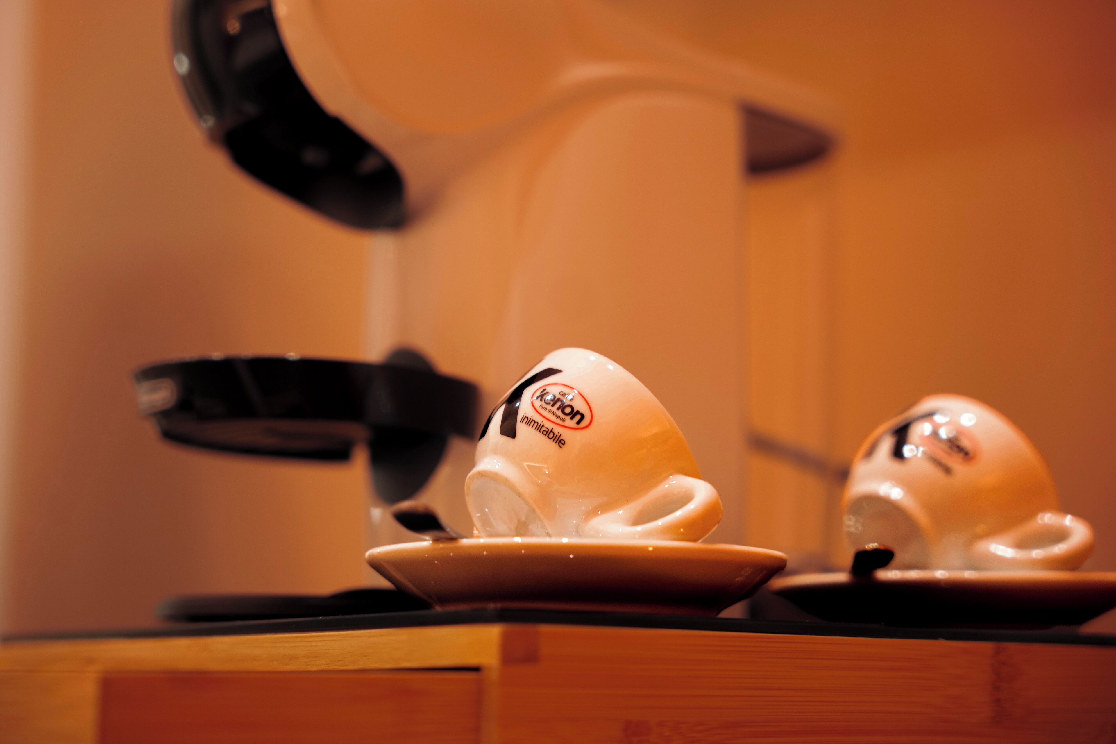A coffee machine with a cup and saucer on a wooden surface.