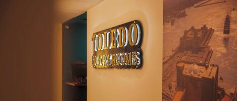 A sign for Toledo Luxury Rooms, a hallway with a view of a castle-like structure.
