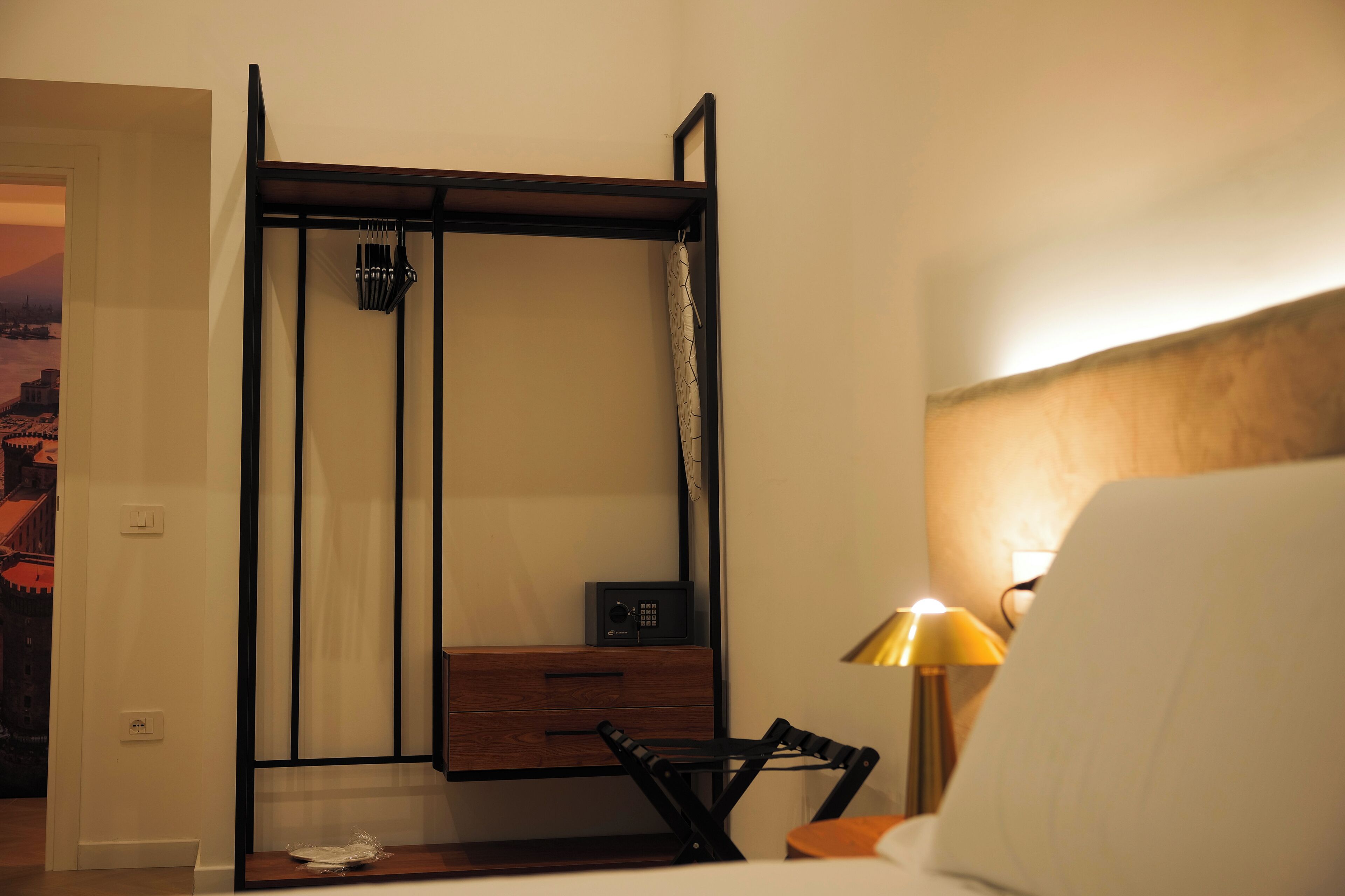 Una stanza con un letto, una scrivania con una sedia, una lampada e una radio fissata al muro.
