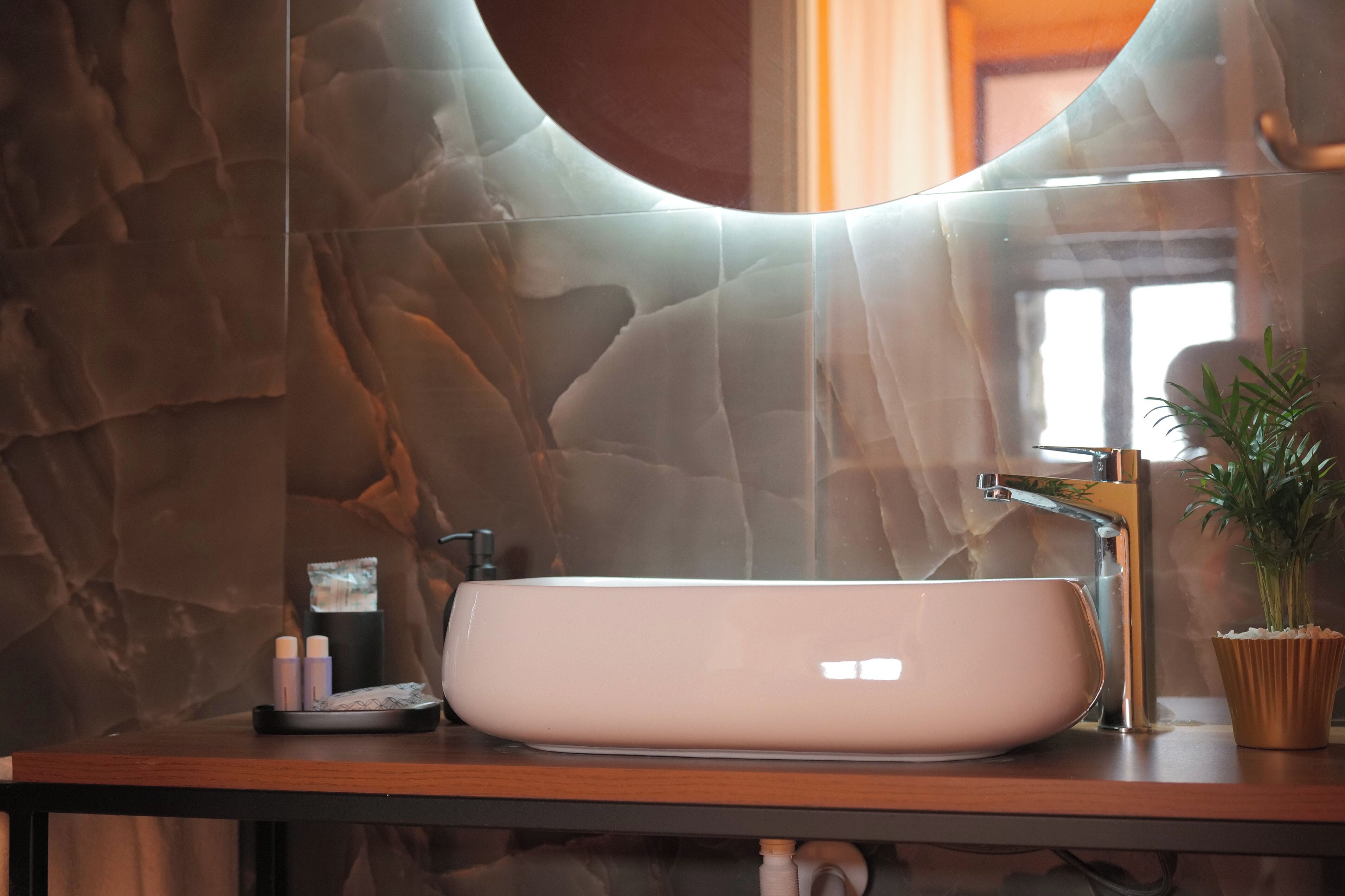 Ein Badezimmer mit einem modernen Waschbecken, einem Spiegel und einer Topfpflanze.