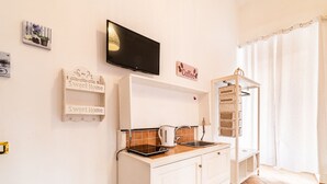 A modern kitchen with a flat-screen TV, a kettle, and a sink. There are two 'Sweet Home' signs on the wall. - Domus Mattei al Duomo By DomusExtra (Naples)