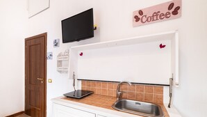 A kitchen with a countertop, sink, and a television mounted above the counter. - Domus Mattei al Duomo By DomusExtra (Naples)
