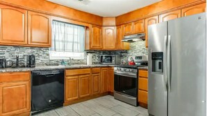 A kitchen with wooden cabinets, a stainless steel refrigerator, a dishwasher, and a stove.
