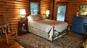A log cabin bedroom with a four-poster bed, two bedside tables with lamps, a dresser, a chair, and a patterned rug. - Appalachian Cabin.North Georgia mountains-Firepit and Hot Tub with great views! (Ellijay)