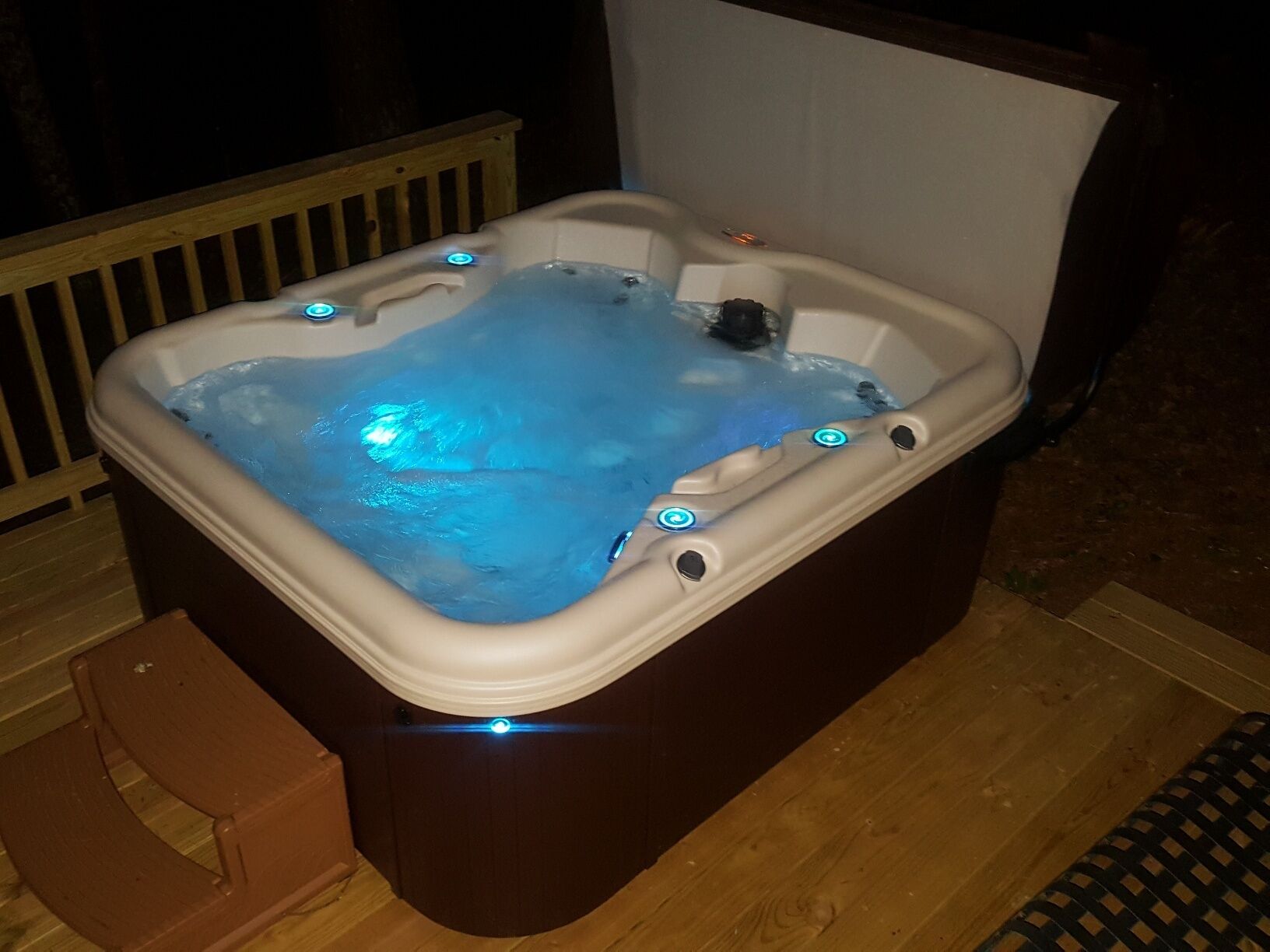 Un bain à remous avec une terrasse en bois et une chaise en bois.