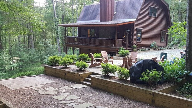 A log cabin with a porch, outdoor seating, and a gravel pathway.
