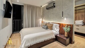 Een moderne slaapkamer met een groot bed, een aan de muur bevestigde televisie en een ingebouwde airconditioning.