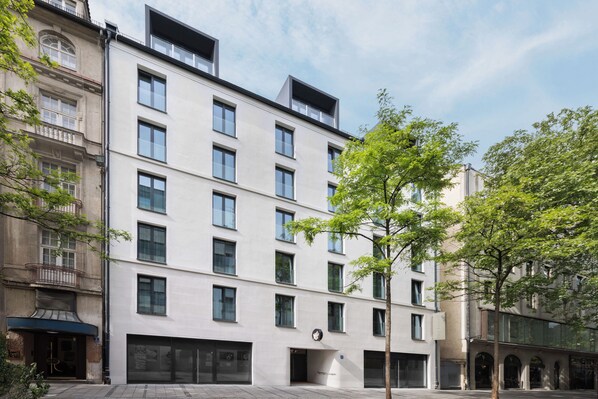 Un edificio moderno de varios pisos con fachada plana, ventanas grandes y una entrada central.