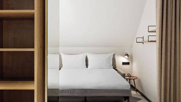 Una habitación de hotel moderna con una cama, una mesita de noche y una pequeña mesa con lámpara.