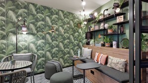 A cozy room with a patterned wallpaper, a wooden bench, a round table, and chairs. - Stay KooooK Munich City (Munich)