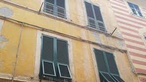Un edificio de varios pisos con paredes amarillas y contraventanas verdes.