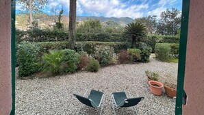 A patio with two chairs, a gravel ground, and a view of a mountainous landscape.