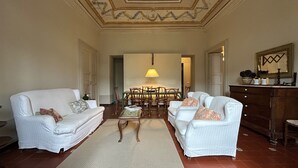 A spacious living room with two white sofas, a coffee table, and a dining table with chairs.