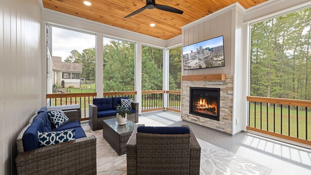 A covered outdoor living area with wicker furniture, a fireplace, and a TV.