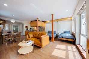 Een moderne woonkamer met een bank, een salontafel en een eethoek met stoelen.