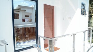 A modern building with a large glass door, a red door, and a small window. - Charming Ocean View (Naval)