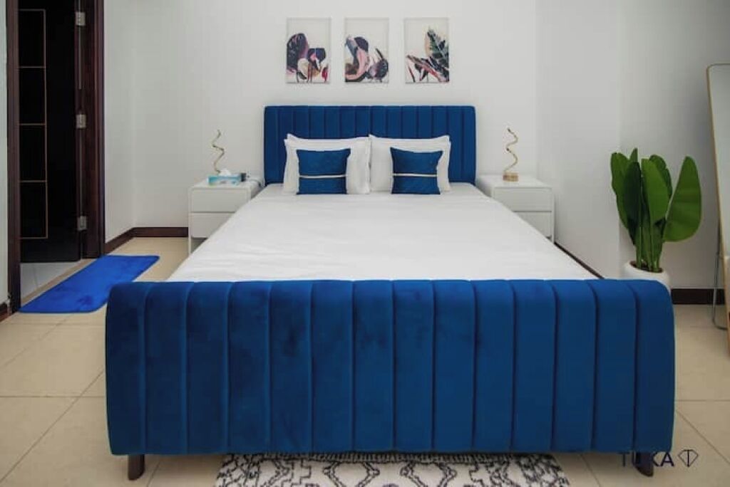 Ein Schlafzimmer mit einem großen Bett, einem Nachttisch, einer Topfpflanze und Bildern an der Wand.