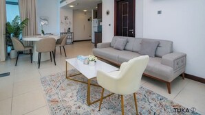 Ein modernes Wohnzimmer mit einer Couch, einem Esstisch und Stühlen. Im Hintergrund befindet sich eine Küche.