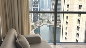Ein modernes Wohnzimmer mit großem Fenster und Blick auf eine Stadtlandschaft und ein Gewässer.