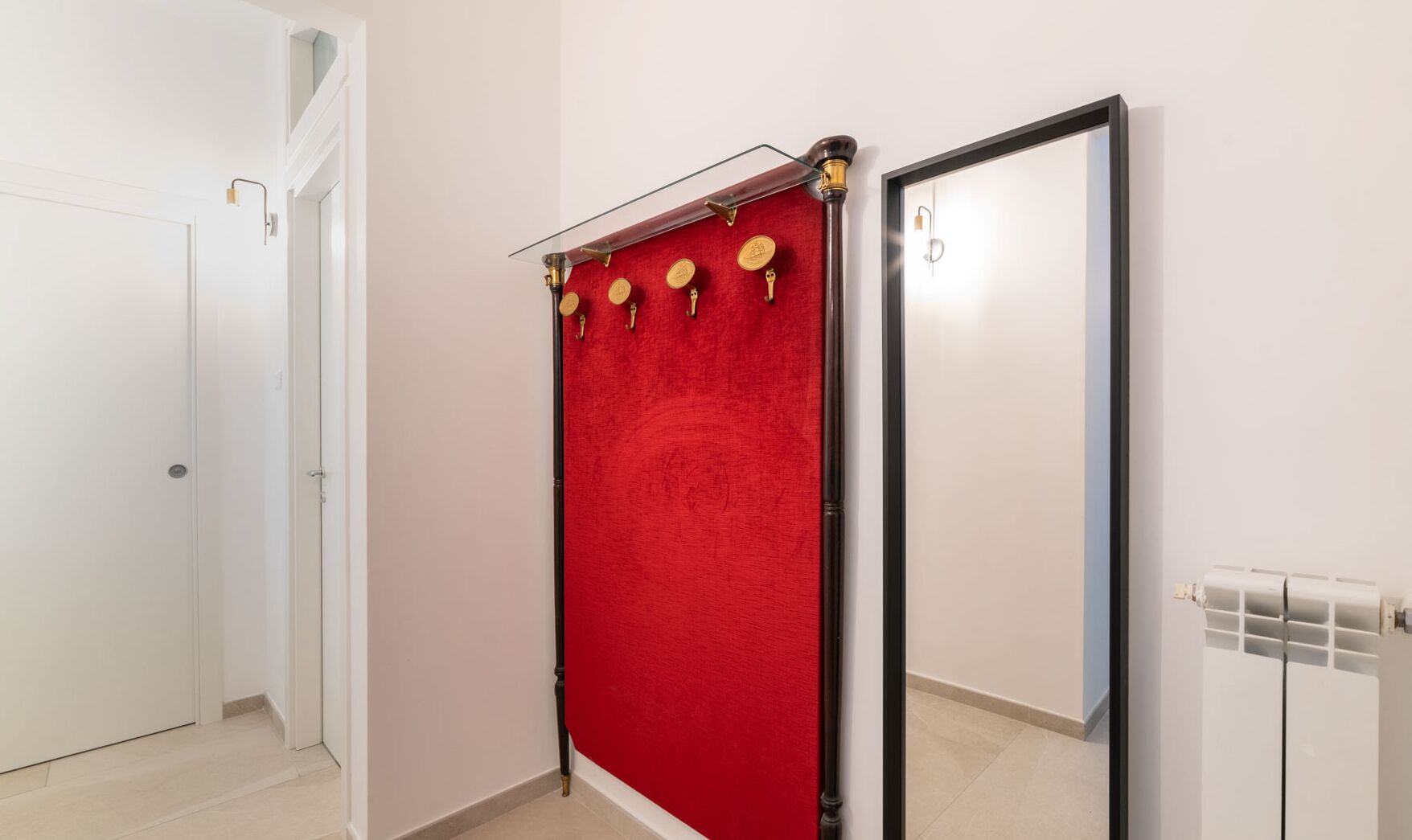 A hallway with a red curtain, a mirror, and a door.