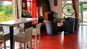 A spacious room with a dining area, a fireplace, and large windows. - Le relais des garrigues (Grisolles)