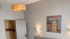 A hotel room with a bed, a wardrobe, a bathroom, and a wall art piece. - Le relais des garrigues (Grisolles)