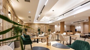 A modern dining area with wooden tables, upholstered chairs, and ambient lighting. - AMAR Design Hotel by HMG (Sofia)