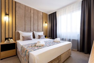 Ein modernes Hotelzimmer mit einem großen Bett, einem Holzkopfende und einem Nachttisch mit Lampe.