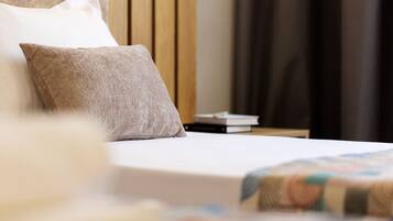 A neatly made bed with a pillow and a quilt, a wooden headboard, and a nightstand with books.