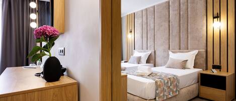 A modern hotel room with a wooden desk, a bed with a beige headboard, and a nightstand.