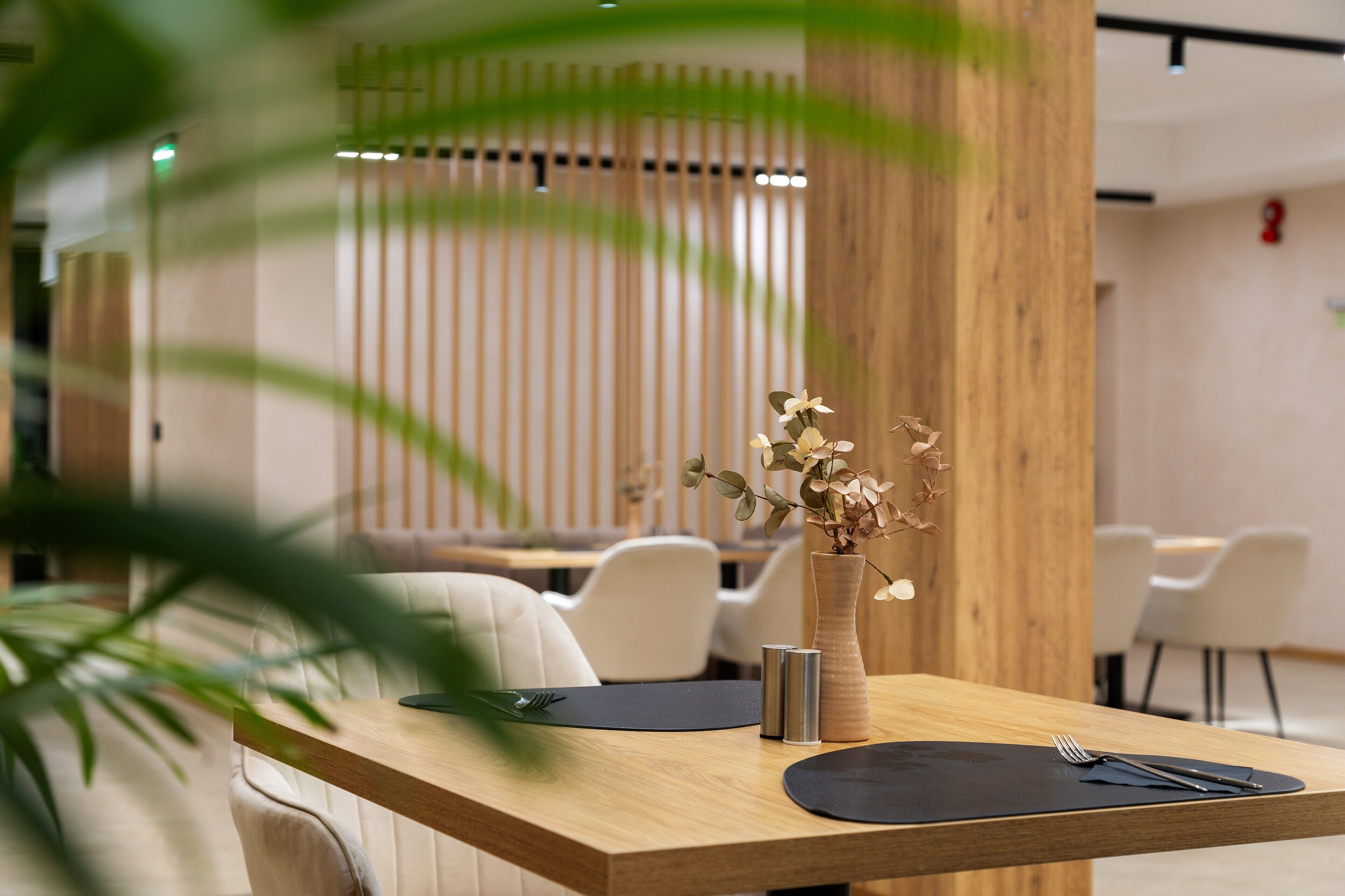 Un comedor moderno con una mesa de madera, un florero con flores y un diseño minimalista.