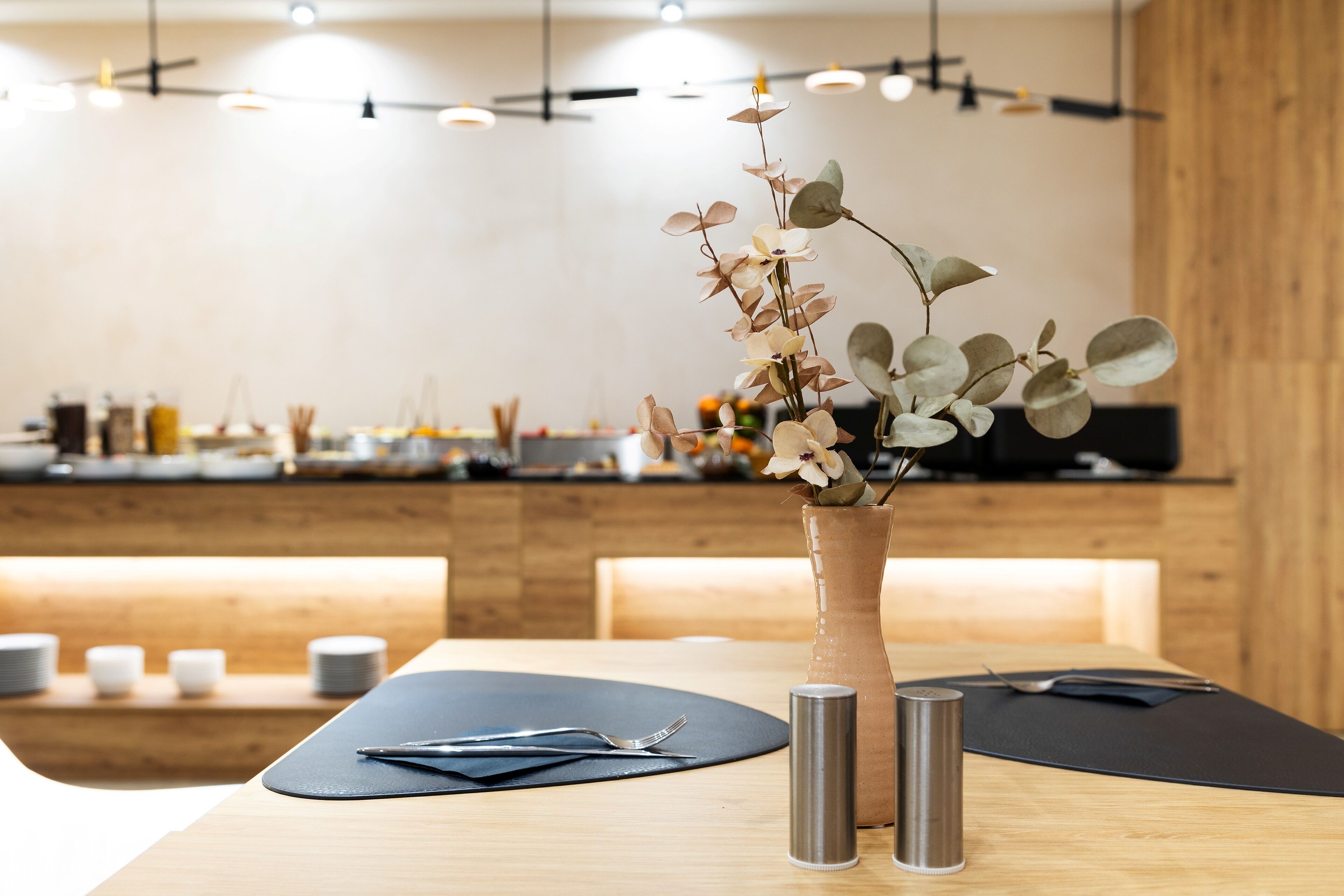 Una mesa de comedor con un florero, un camino de mesa negro y un candelabro de metal.