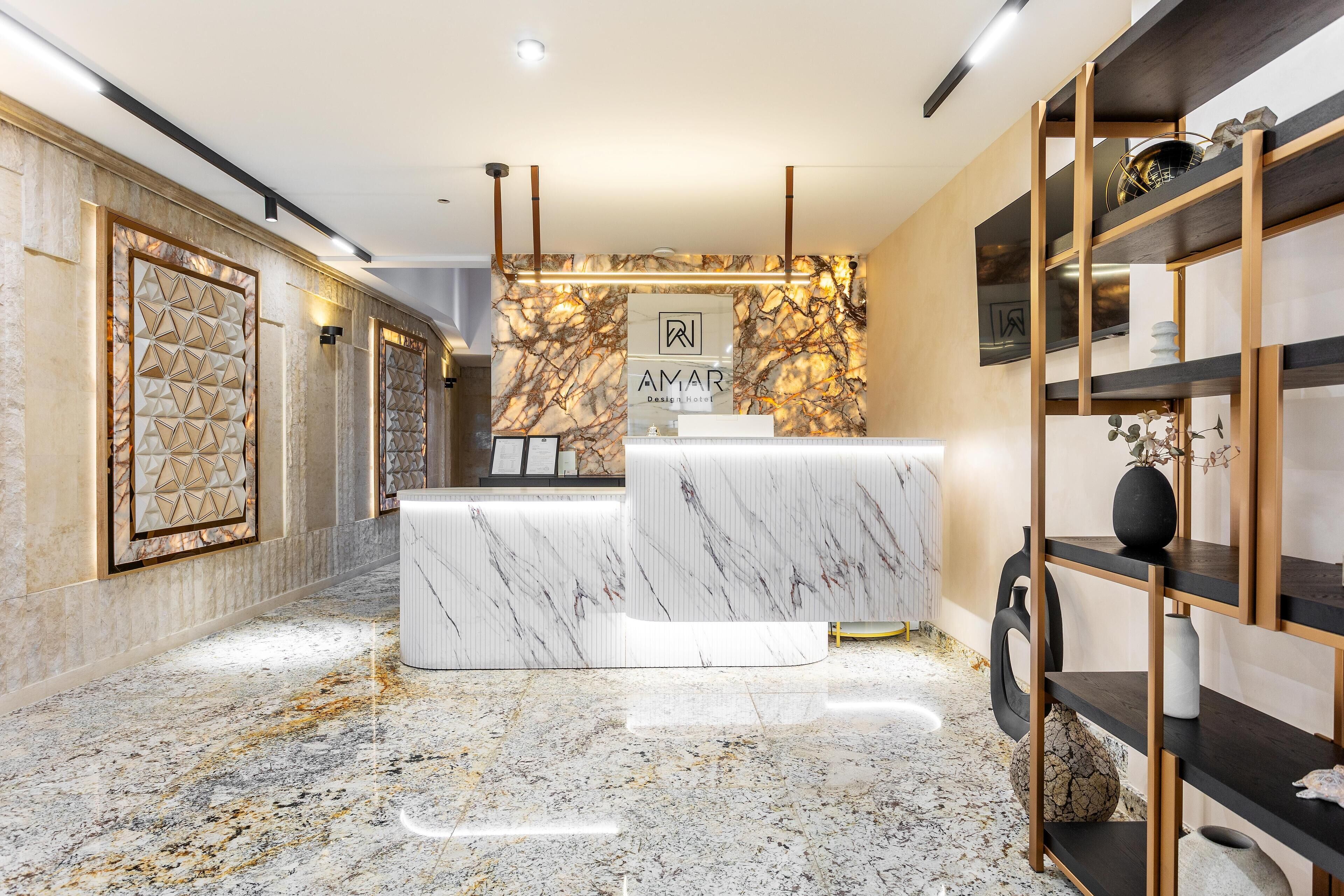 A modern hotel reception area with marble flooring, a reception desk, and a wall-mounted sign.
