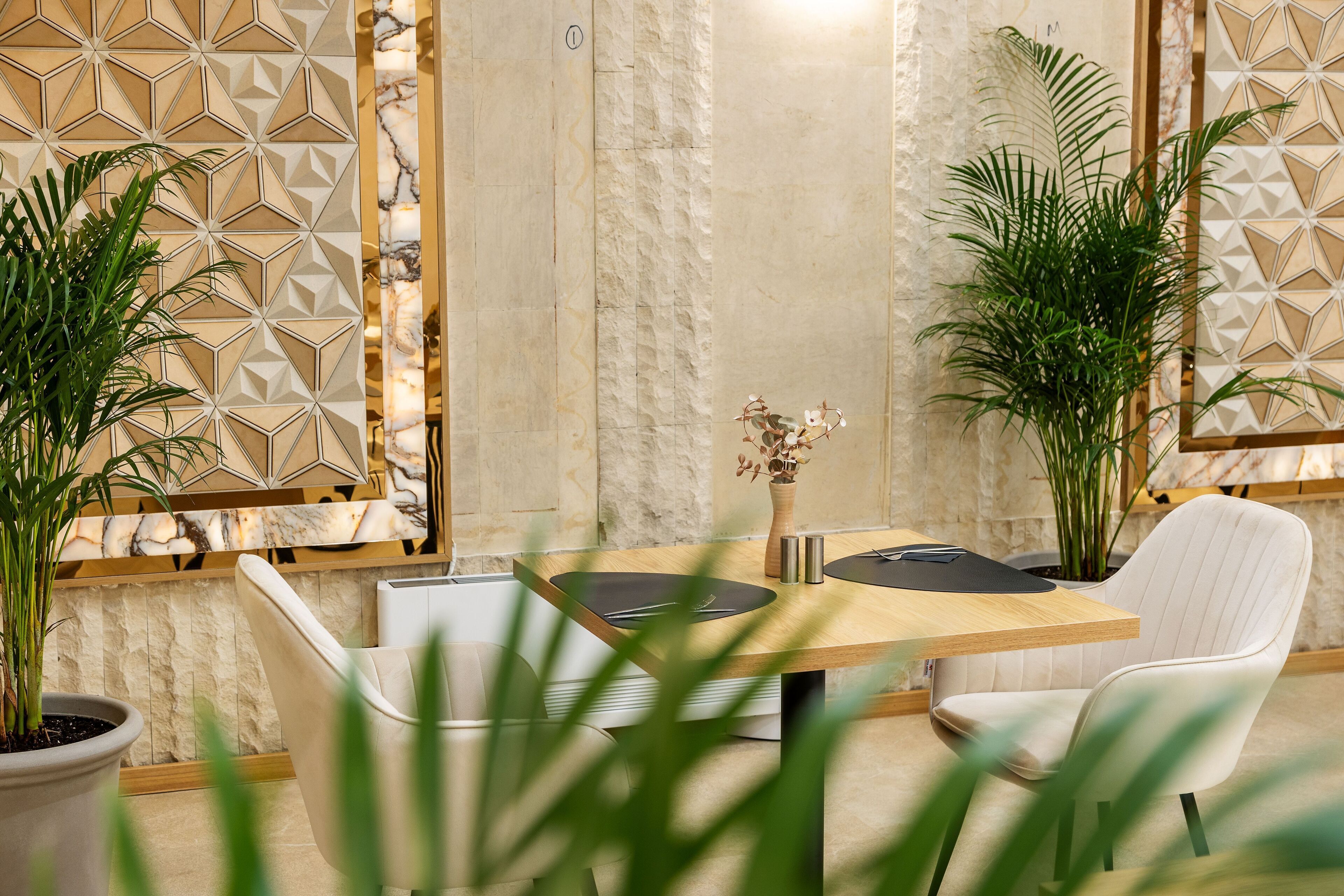 A modern dining area with a wooden table, white upholstered chairs, and decorative wall panels.